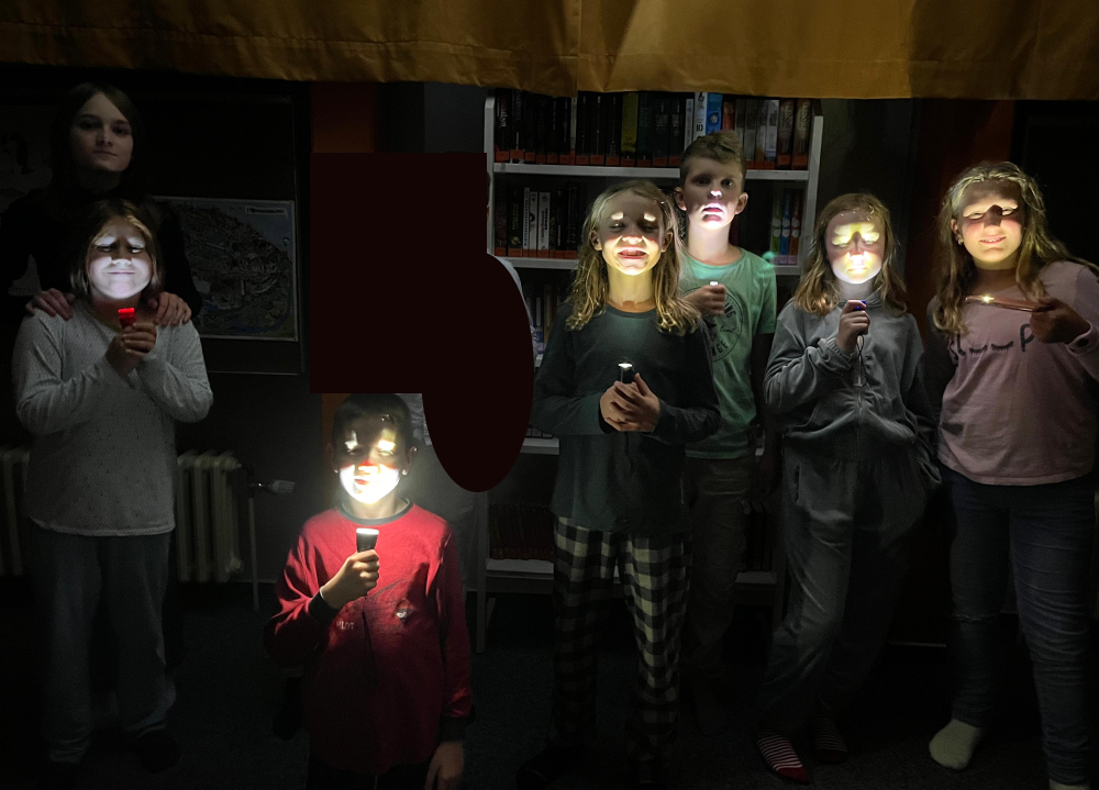 Schüler:innen beleuchten ihre Gesichter mit Taschenlampen
