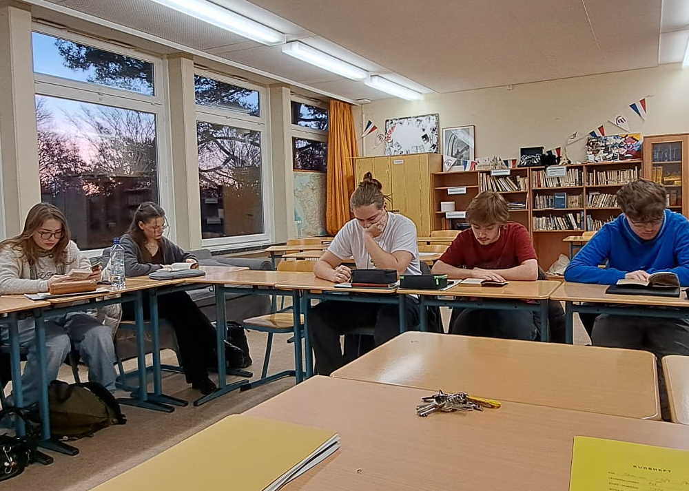Oberstufenschüler:innen lesen im Klassenraum