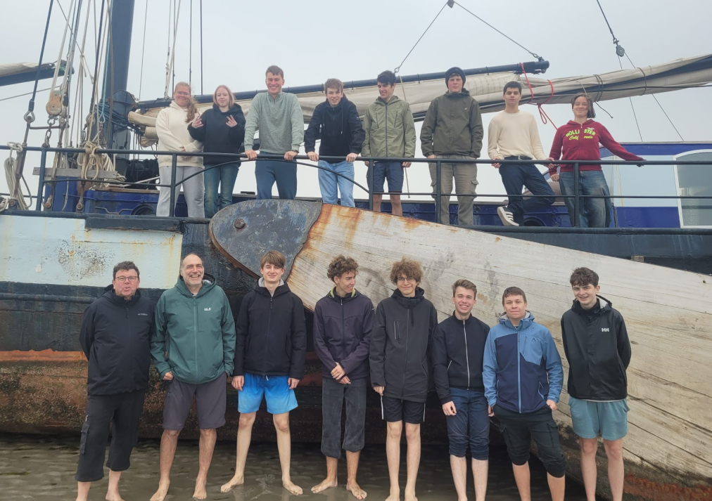 Schülergruppe vor Schiff auf Ebbe