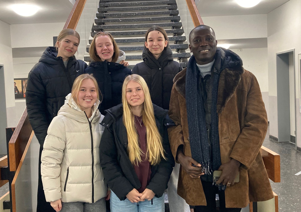 Bild von einem Lehrer aus Ghana mit Schüler:innen der 9c