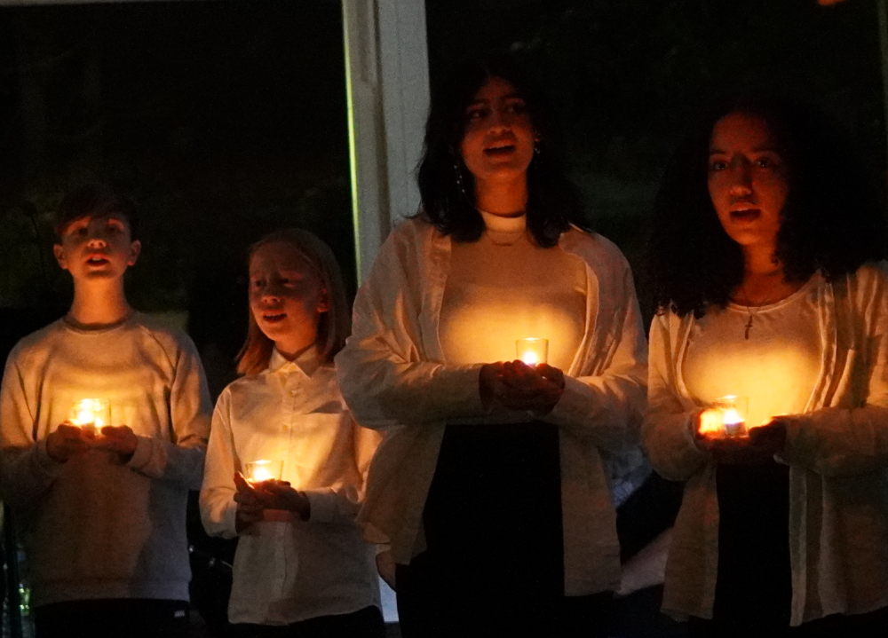 Schüler:innen singen mit Kerzen