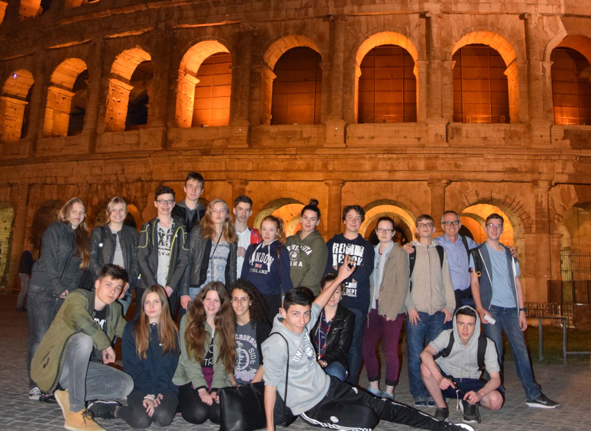 Lateinklasse als Gruppenbild vor dem beleuchteten Kolosseum in Rom bei Nacht