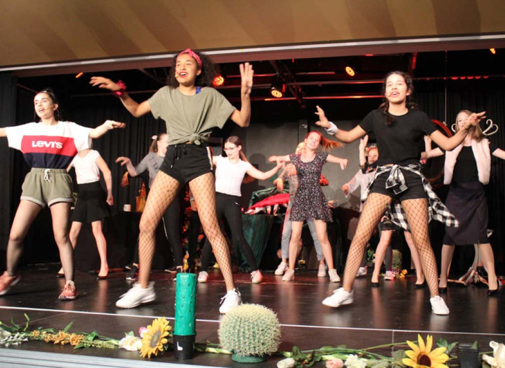 Schüler:innen beim tanzen während einer Musical Aufführung auf der schuleigenen Bühne