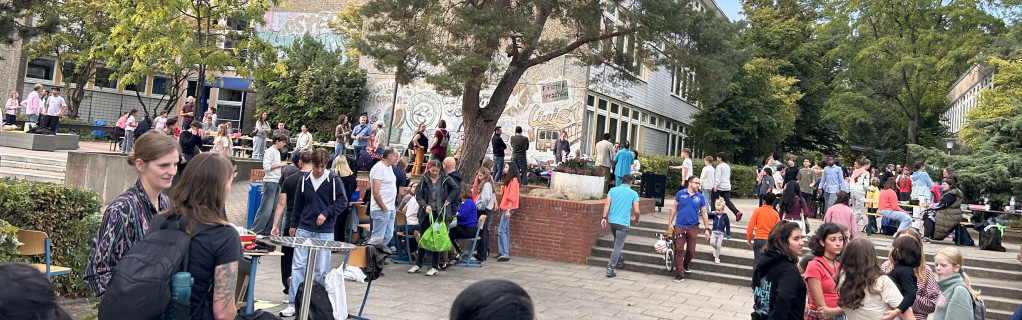 Familien bunt gekleidet auf dem Schulhof im Rahmen der bunten Tafel